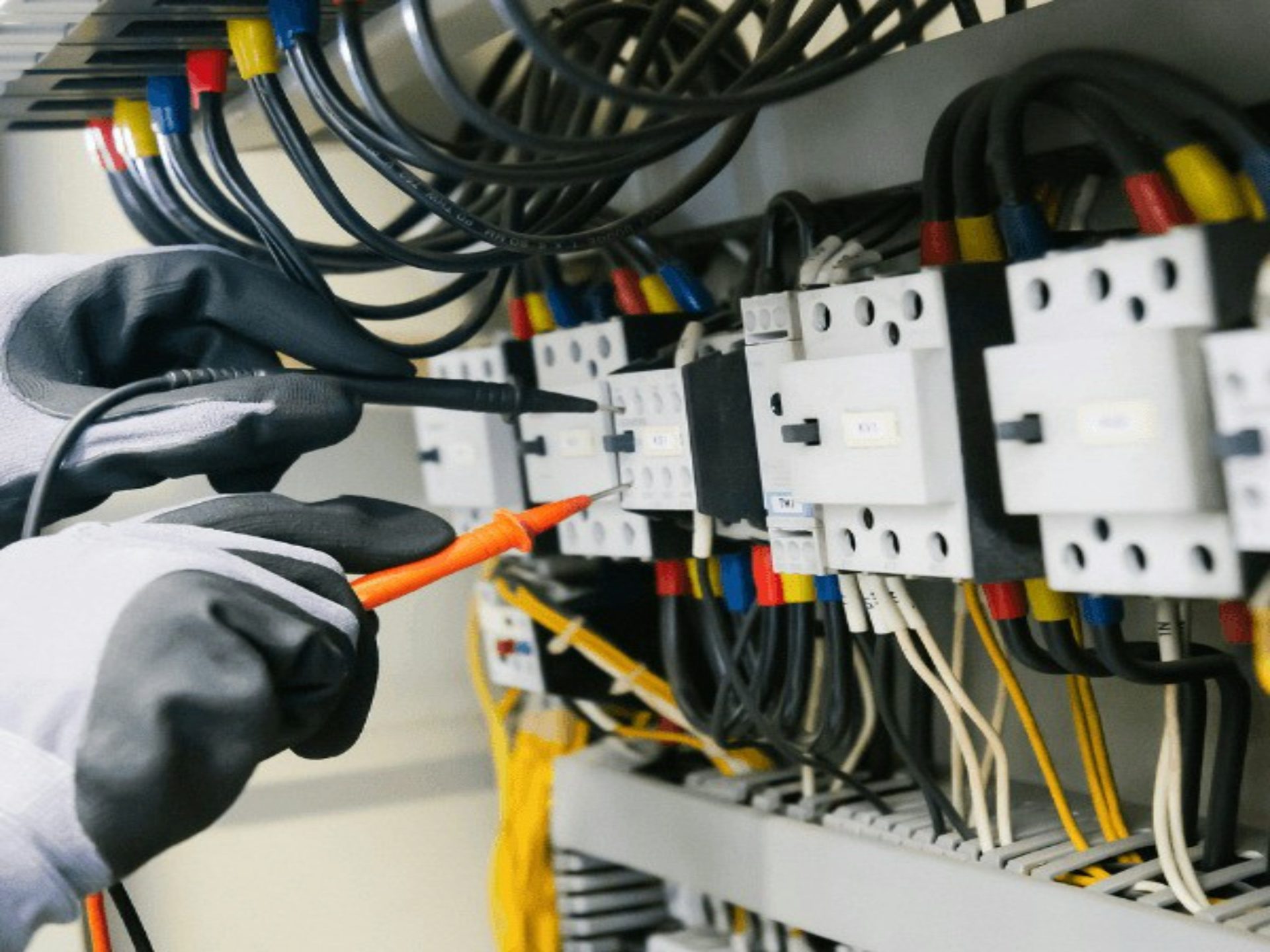 Elektriker prüft einen Sicherungskasten mit einem Multimeter.